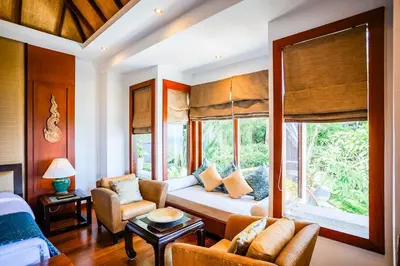 a room with a bed and a couch and a window at Villa Talay in Surin Beach