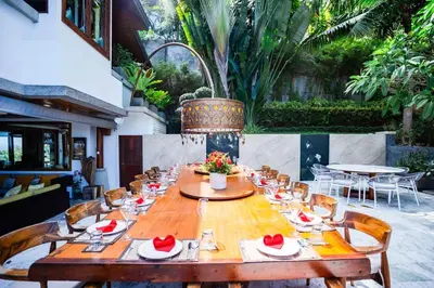 a long wooden table with chairs and a tableasteryasteryasteryasteryasteryasteryastery at Villa Talay in Surin Beach