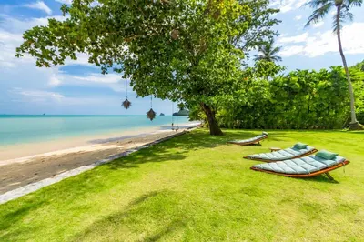 two boats sitting on the grass next to the beach at Baan Klong II in Ko Yao Noi