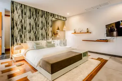 a bedroom with a large white bed and a tv at Baan Kloi II in Ban Na Tai