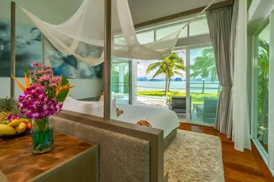 a bedroom with a bed and a vase of flowers on a table at Baan Klong IV in Ko Yao Noi
