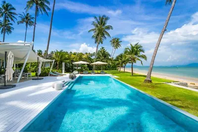 a swimming pool next to a beach with palm trees at Baan Klong IV in Ko Yao Noi