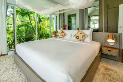 a bedroom with a large white bed with a large window at Baan Klong in Ko Yao Noi
