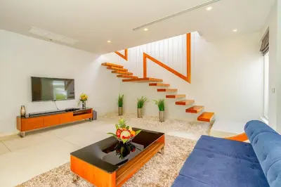 a living room with a blue couch and stairs at Baan Kloi IV in Ban Na Tai