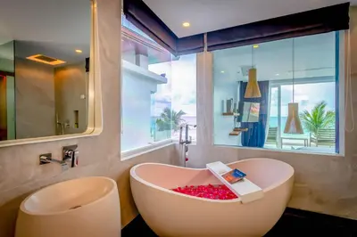 a bathroom with a bath tub with a large window at Baan Kloi in Ban Na Tai