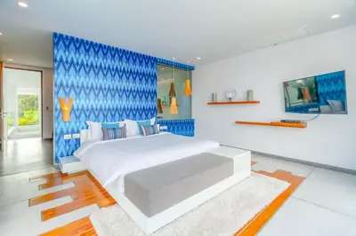 a bedroom with a large bed with a blue wall at Baan Kloi in Ban Na Tai