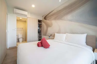 a large white bed with two red pillows on it at Fairway Escape - Golf View 1BR with Balcony in Laguna in Laguna Phuket