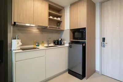 a kitchen with white cabinets and a black refrigerator at Fairway Escape - Golf View 1BR with Balcony in Laguna in Laguna Phuket
