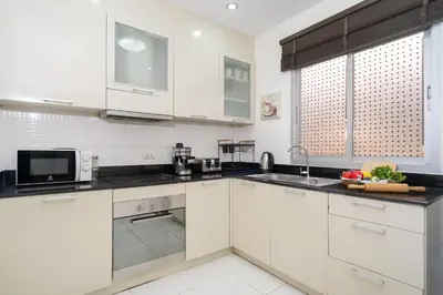 a kitchen with white cabinets and black counter tops at Laguna Townhouse with Jacuzzi bathtub, Bang Tao beach in Laguna Phuket
