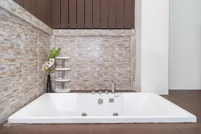 a white bath tub in a room with a brick wall at Laguna Townhouse with Jacuzzi bathtub, Bang Tao beach in Laguna Phuket