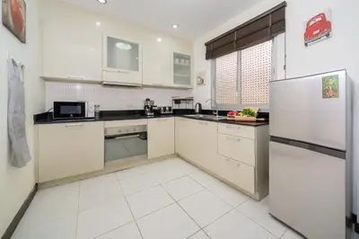 a kitchen with white cabinets and a refrigerator at Laguna Townhouse with Jacuzzi bathtub, Bang Tao beach in Laguna Phuket