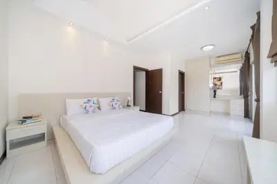 a white bedroom with a large bed and a bathroom at Laguna Townhouse with Jacuzzi bathtub, Bang Tao beach in Laguna Phuket