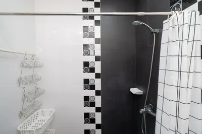 a bathroom with a shower with black and white tiles at Laguna Townhouse with Jacuzzi bathtub, Bang Tao beach in Laguna Phuket