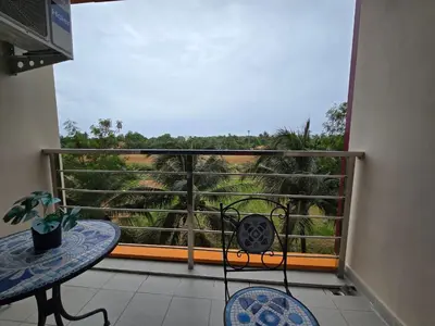 a balcony with a table and a view of trees at 777 Beach Condotel in Mai Khao Beach