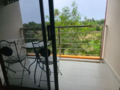 a balcony with a table and chairs and a window at 777 Beach Condotel in Mai Khao Beach