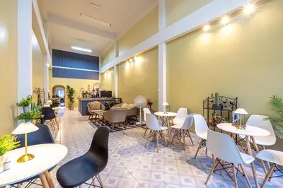 a restaurant with tables and chairs in a room at 113 Yellow House Hostel in Phuket Town