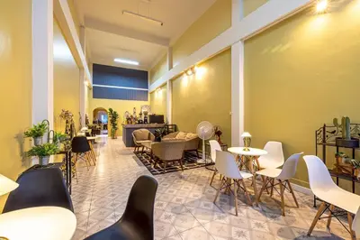 a restaurant with tables and chairs in a room at 113 Yellow House Hostel in Phuket Town