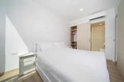 a white bedroom with a white bed and a closet at Skypark Laguna Garden View Bang Tao Beach in Laguna Phuket