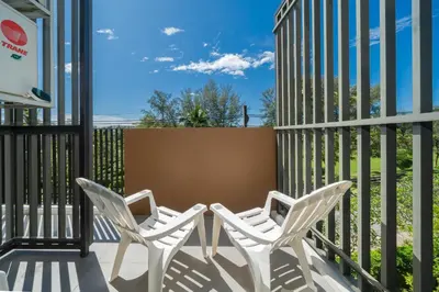 two white chairs sitting on a porch with a fence at Skypark Laguna Garden View Bang Tao Beach in Laguna Phuket