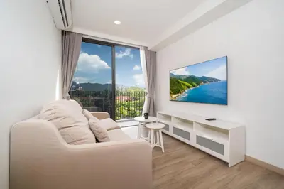 a living room with a white couch and a large window at Skypark Laguna Bang Tao Beach in Laguna Phuket