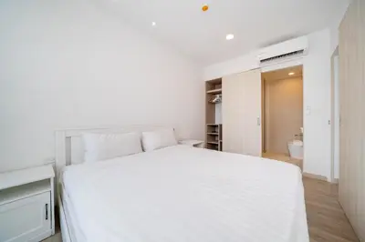 a white bedroom with a white bed and a bathroom at Skypark Laguna Bang Tao Beach in Laguna Phuket