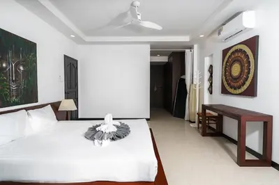 a bedroom with a white bed and a table at Noksawan Villa by G Estate in Rawai Beach