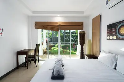 a bedroom with a bed and a table and a desk at Noksawan Villa by G Estate in Rawai Beach