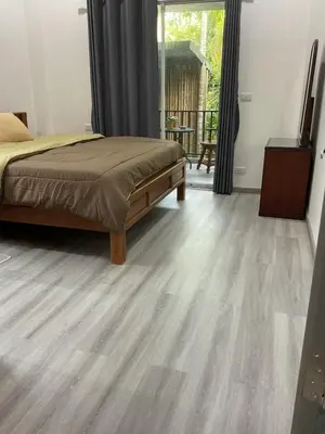 a bedroom with a bed and a wooden floor at Jampun Pool Villa in Klong Muang Beach