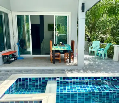 a pool in front of a house with a table and chairs at Jampun Pool Villa in Klong Muang Beach