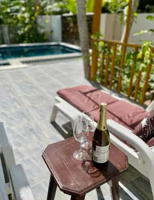 a bottle of wine sitting on a table with two glasses at Jampun Pool Villa in Klong Muang Beach