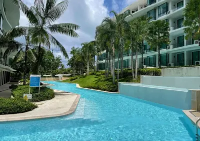 a swimming pool in front of a building with palm trees at Luxurious 5-star Apartment in Rawai Beach
