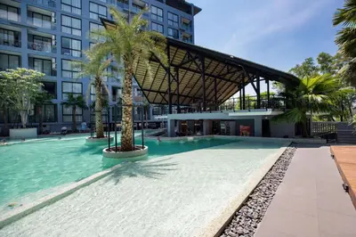 a swimming pool with palm trees in front of a building at Tropics Kamala Hill View Apartment CTG D704 near Beach and Fantasea in Kamala Beach