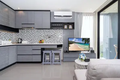 a living room with a kitchen and a tv in it at Tropics Kamala Hill View Apartment CTG D704 near Beach and Fantasea in Kamala Beach