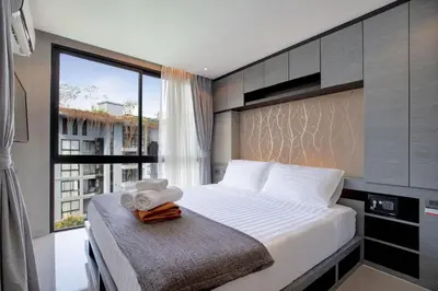 a bedroom with a large bed with a window at Fun, Beach & Topical Vibes! Pool View 2BR Apartment CTG P603-4 in Tropics Kamala Residence in Kamala Beach