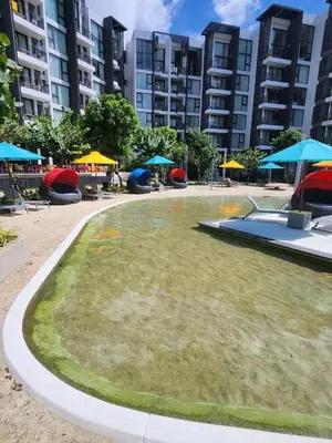 a large yard with chairs and umbrellas and buildings at Cassia Loft Laguna Phuket Bang Tao Beach in Laguna Phuket