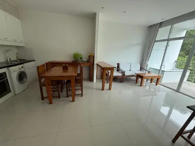 a living room with a table and chairs and a kitchen at Grand kamala falls in Kamala Beach