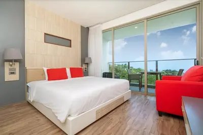 a bedroom with a large bed and a red chair at Prime Location Kamala Ocean View Suite OCN C64 just 450m to the Beach in Kamala Beach