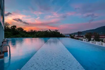 a large swimming pool with a sunset in the background at Kamala Ocean View 2BR Apartment OCN C35, just 5 min walk to the Beach in Kamala Beach