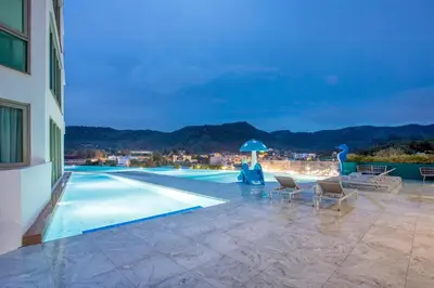 a swimming pool with chairs and an umbrella on a building at Kamala Ocean View 2BR Apartment OCN C35, just 5 min walk to the Beach in Kamala Beach