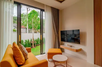 a living room with a couch and a large window at Narinsaya Pool villas in Nai Yang Beach