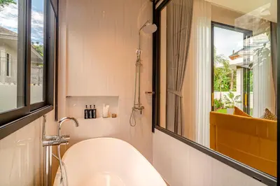 a bathroom with a bath tub and a window at Narinsaya Pool villas in Nai Yang Beach