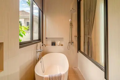 a bathroom with a tub and a sink and a window at Narinsaya Pool villas in Nai Yang Beach
