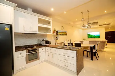 a kitchen with white cabinets and a dining room at Laguna Luxure Private Pool Villa in Layan Beach