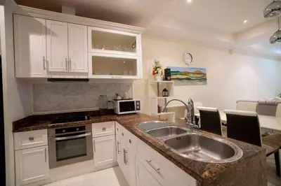 a kitchen with white cabinets and a sink at Laguna Luxure Private Pool Villa in Layan Beach