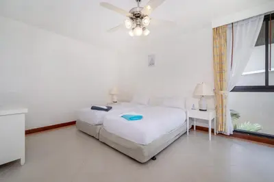 a white bedroom with a bed and a ceiling fan at Allamanda Townhouse Laguna Phuket Bang Tao Beach in Laguna Phuket