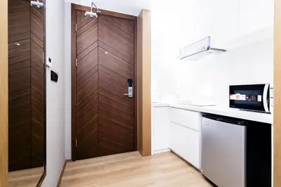 a kitchen with a wooden door and a microwave at Suite Aura 1BR PoolsGyms Shuttle to Nai Harn in Rawai Beach
