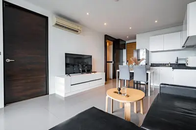 a kitchen and living room with a table and chairs at Suite Lumi 1BR Rooftop Pool ReLife Nai Harn in Chalong