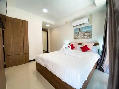 a bedroom with a bed with white sheets and red pillows at ARIA Condo 1BR Pool View NBC Nai Harn in Phuket Town