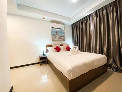 a bedroom with a bed with white sheets and red pillows at ARIA Condo 1BR Pool View NBC Nai Harn in Phuket Town