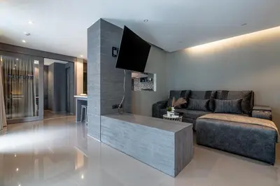 a living room with a couch and a flat screen tv at Suite Altair 2BRPool RooftopBarCitygate Kamala in Phuket Town